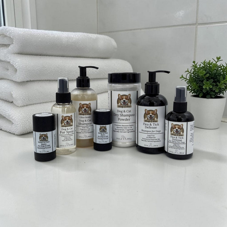 Collection of pet care products, including shampoos, sprays and powders, on a bright with bathrooom counter with folded white towels.