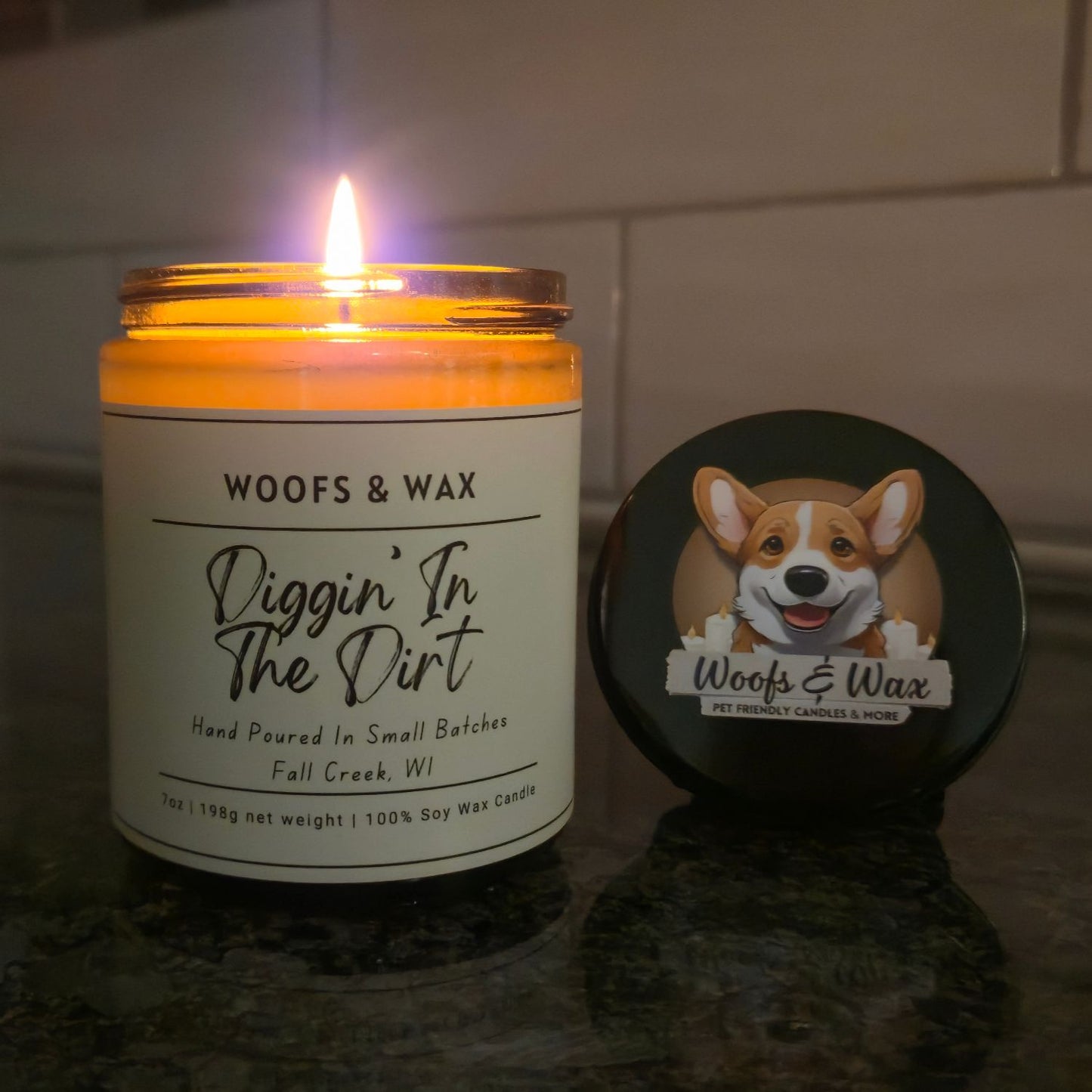 Candle with 'Woofs & Wax' label and a coaster featuring a dog illustration on a reflective surface.