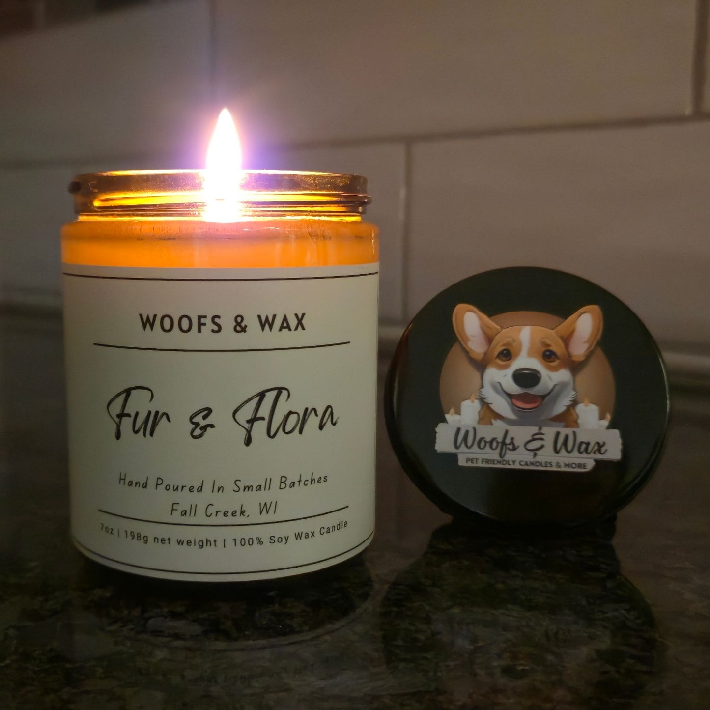 Candle with 'Woofs & Wax' label and a dog illustration on a dark surface.