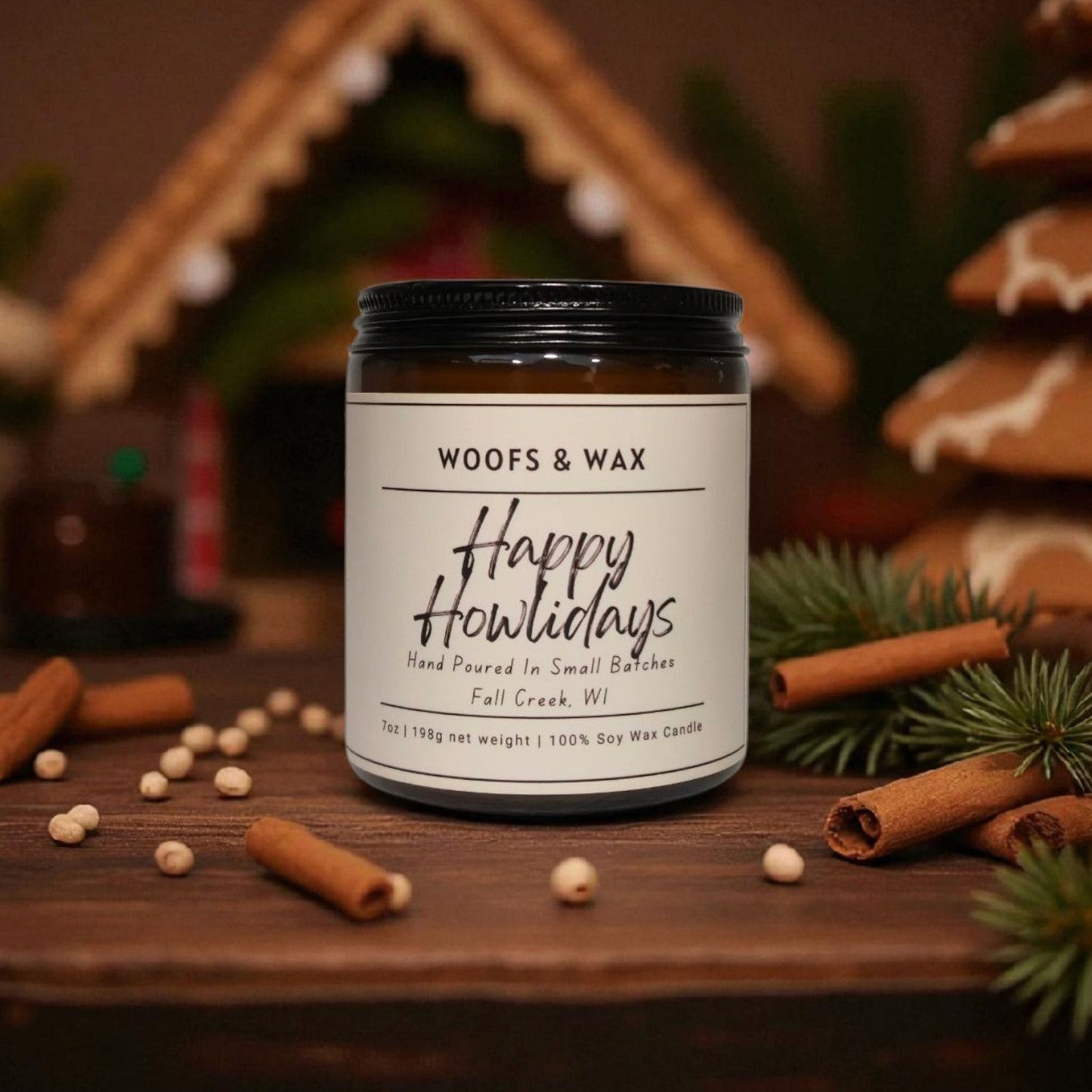 Candle jar labeled 'Happy Howliodays' by Woofs & Wax on a wooden surface with cinnamon sticks and pine branches.