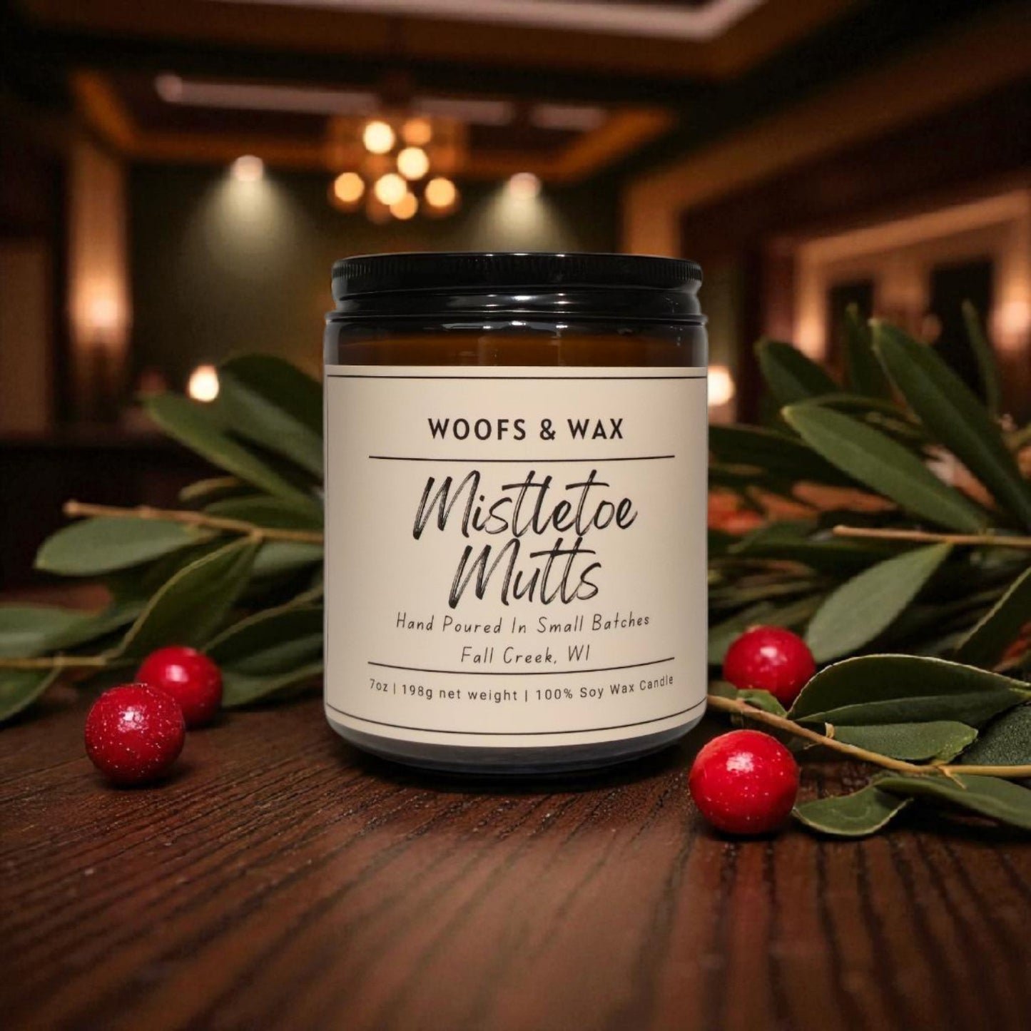 Candle jar labeled 'Woofs & Wax Mistletoe Mutts' on a wooden surface with mistletoe and berries.