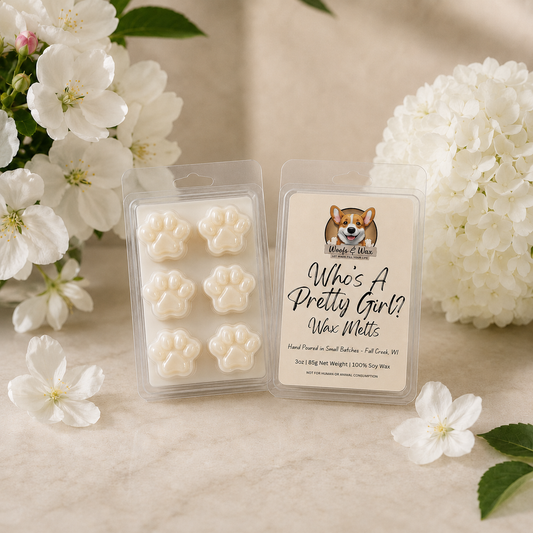 Packaged wax melts with a dog illustration and text, surrounded by white flowers on a light background