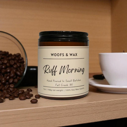 Candle labeled 'Woofs & Wax Ruff Morning' on a wooden surface with coffee beans and a cup.