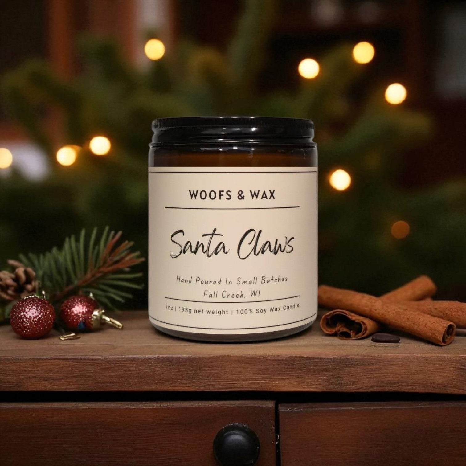 Candle labeled 'Woofs & Wax Santa Claws' on a wooden surface with festive decorations.