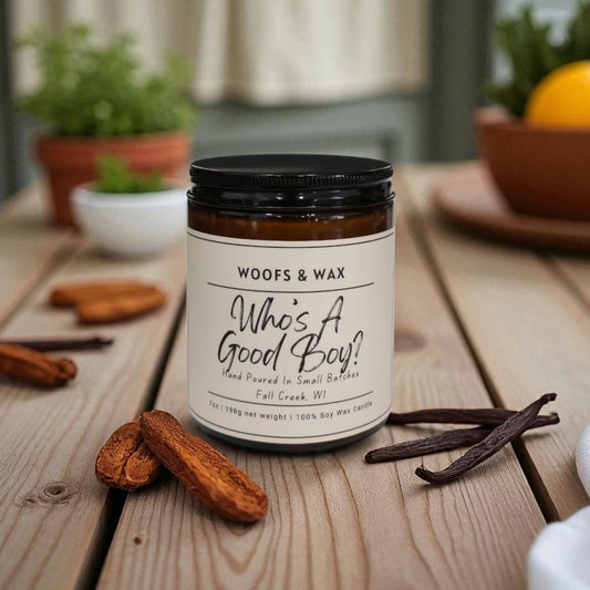 Jar of 'Woofs & Wax' candle on a wooden table with vanilla beans and sandalwood.