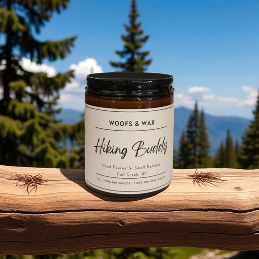 Jar of 'Hiking Buddy' candle by Woofs & Wax on a wooden log with a forest background