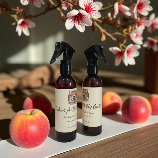 Two spray bottles with labels next to peaches and apple blossoms on a wooden surface.